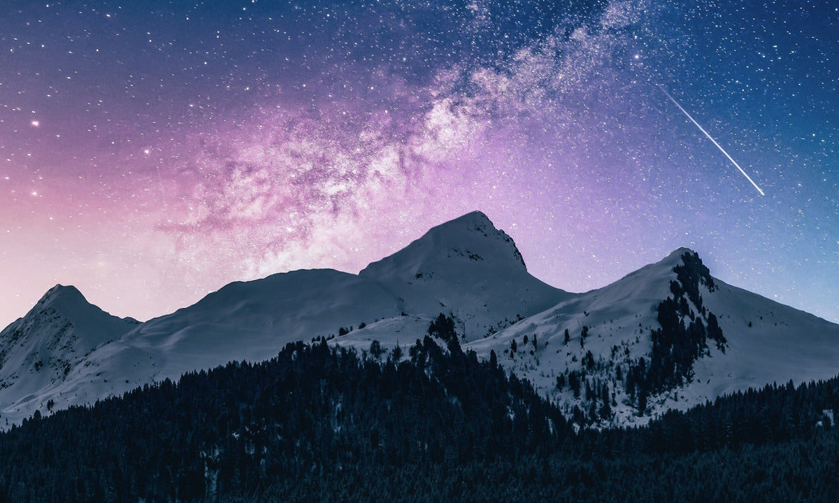 Mountains at dusk with a shooting star in the sky
